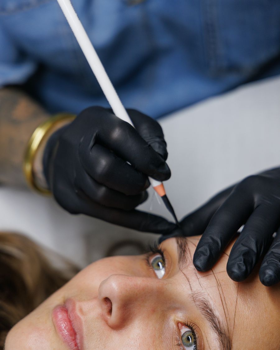 Gros plan sur le tracé des sourcils au crayon, mains gantées de Marie