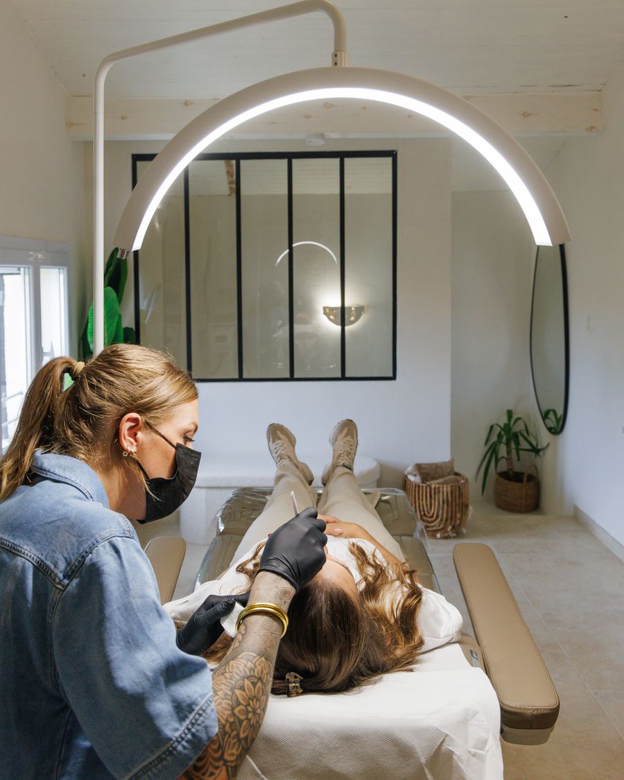 Cliente allongée pendant une prestation de maquillage permanent des sourcils