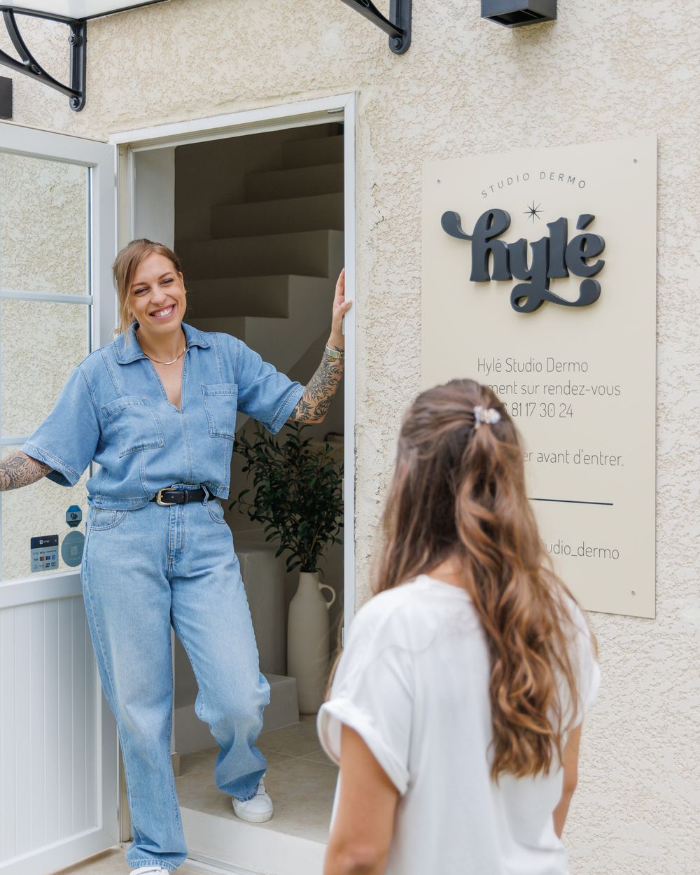 Marie ouvre la porte du studio Hylé à une cliente à son arrivée