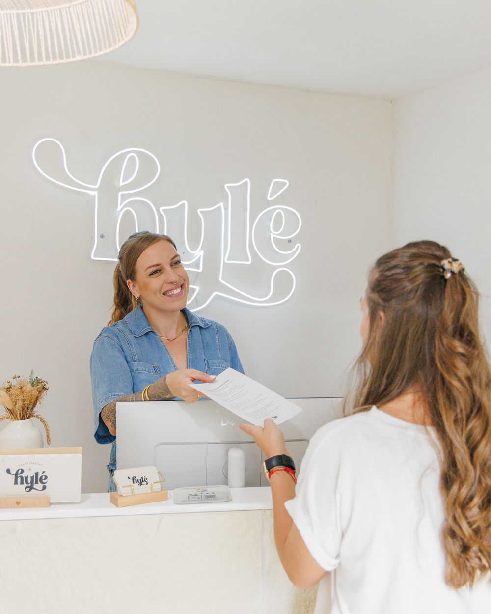 Marie remet un document à sa cliente au comptoir du studio Hylé après la prestation