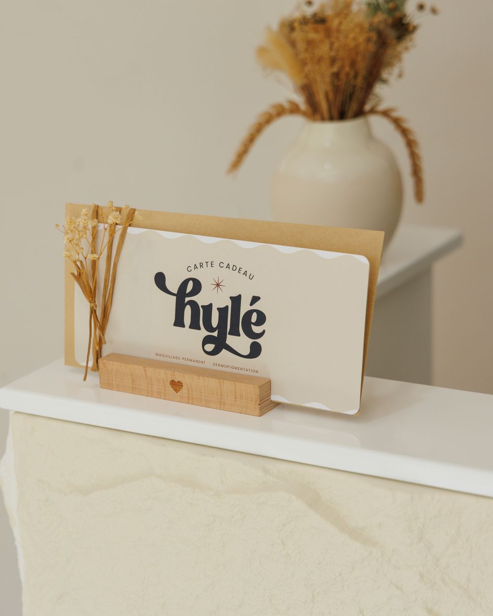 Carte cadeau Hylé présentée sur le comptoir du studio, avec fleurs séchées