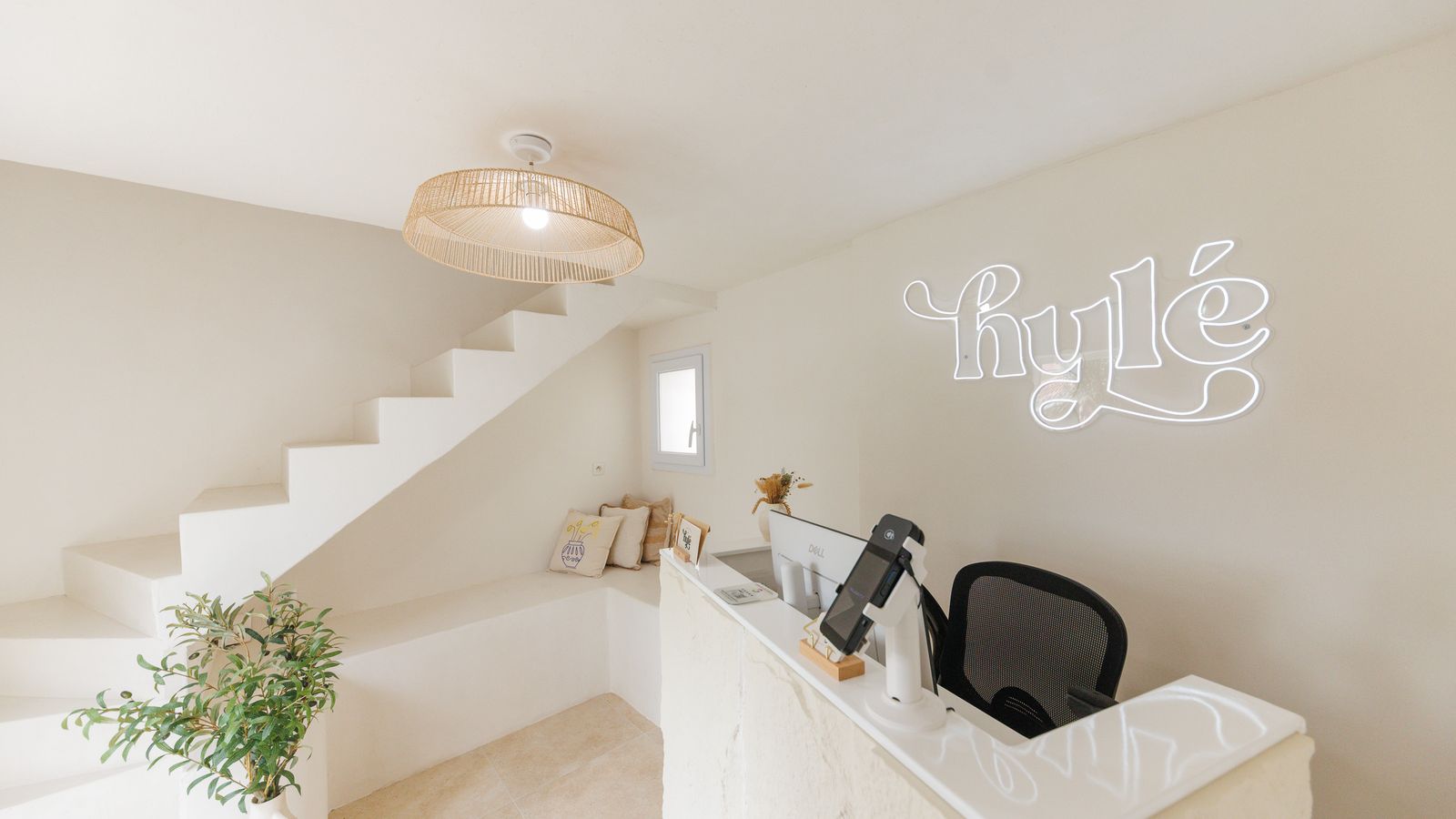 Espace d'accueil de Hylé Studio Dermo à Biguglia : réception, escalier blanc et enseigne néon Hylé